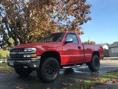 a red pick up truck parked in front of a tree