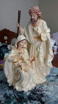 a statue of jesus and baby jesus holding a stick on top of a blue blanket