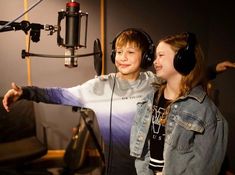 two young people in front of a microphone with headphones on