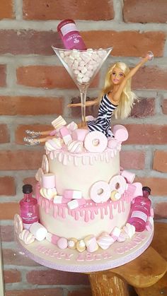 a barbie doll standing on top of a cake with a martini glass in the middle