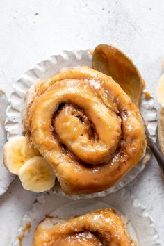 two pieces of banana bread sitting on top of a paper plate next to some sliced bananas