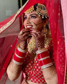 a woman dressed in red and gold holding her hands up to her face while posing for the camera