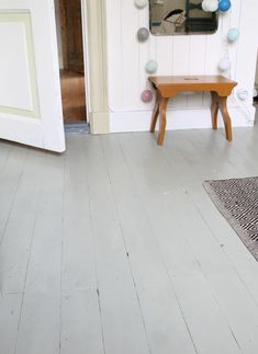 a room with white walls and wooden flooring next to a mirror on the wall