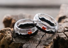 two wedding rings with red stones on them sitting on top of a piece of wood