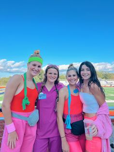 three women in pink and orange outfits posing for the camera with one woman holding a drink