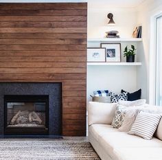 a living room filled with furniture and a fire place in front of a wall mounted fireplace