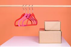 three pink hangers are hanging from a clothes line next to boxes on a shelf