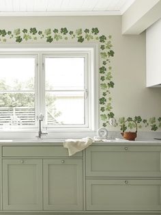 a kitchen with white cabinets and green wallpaper on the walls, along with an open window