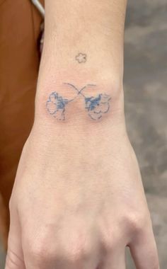 a person with a butterfly tattoo on their left wrist and the other hand behind them