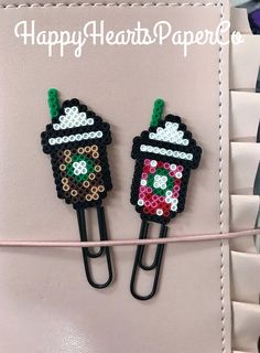 two black clips with cupcakes on them are hanging from a pink cord that is attached to a wall