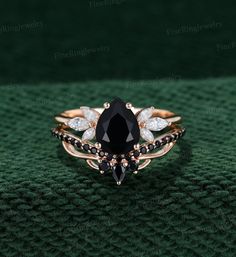 a black and white diamond ring sitting on top of a green surface with diamonds in the middle