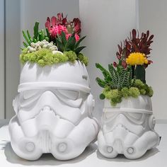 two white vases with flowers and plants in them