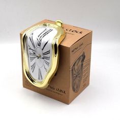 a gold and white clock sitting on top of a cardboard box next to it's packaging