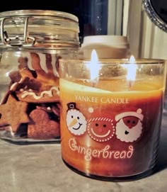 a candle that is sitting on a counter next to some cookies in a glass jar