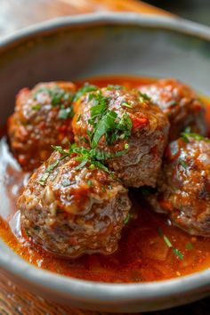 three meatballs in tomato sauce with parsley on top