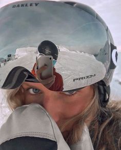 a woman taking a selfie with her ski goggles on while wearing a helmet