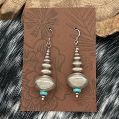 This Is A Beautiful Pair Of Vintage Sterling Silver Navajo-Made Statement Dangle Earrings. The Earrings Feature Handmade Saucer Beads That Graduate In Size From 4mm To 19mm, Creating A Striking And Elegant Look. These Saucer Beads Are Accented With Round Beads And Turquoise Heishi, Adding A Touch Of Color And Texture To The Design. With A Total Length From The Top Of The Hook Of 2.25” And A Total Weight Of 14 Grams, These Earrings Make A Perfect Statement Piece For Any Occasion. Product Details: Decade: 1980s (Estimated) Material: Sterling Silver Beads: Handmade Saucer Beads Size Range: 4mm To 19mm Accents: Round Beads And Turquoise Heishi Total Length From T Silver Bohemian Earrings With Large Beads, Southwestern Silver Beaded Earrings, Southwestern Silver Dangle Beaded Earrings, Silver Southwestern Style Dangle Beaded Earrings, Silver Dangle Earrings With Large Beads, Silver Southwestern Beaded Earrings, Beads Handmade, Accessories Jewelry Earrings, Native American Jewelry