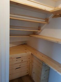 an empty closet with wooden shelves and drawers