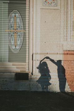 the shadow of a person standing in front of a building with a cross on it