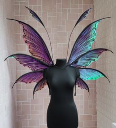 a black mannequin with purple and green butterfly wings on it's head