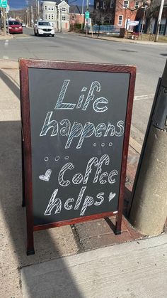 a sign on the sidewalk that says life happens, coffee helps and is written in chalk