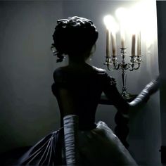 a woman standing in front of a chandelier with candles