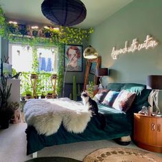 a cat sitting on the edge of a bed in a room with plants and pictures