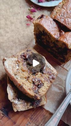 two pieces of bread sitting on top of a wooden cutting board next to a knife and fork