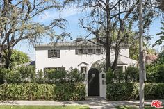 a white house surrounded by trees and bushes