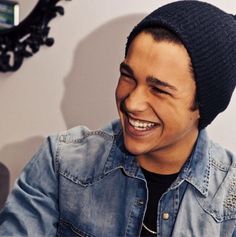 a smiling man wearing a denim jacket and a beanie