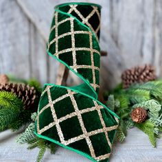 two green velvet christmas stockings with gold sequins and pine cones in the background