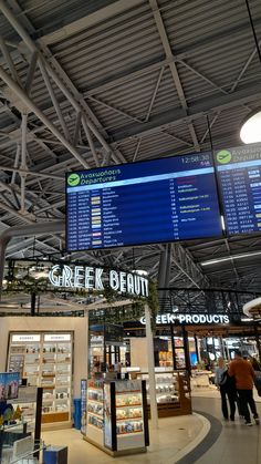 people are walking around in an airport with information on the wall and ceiling above them