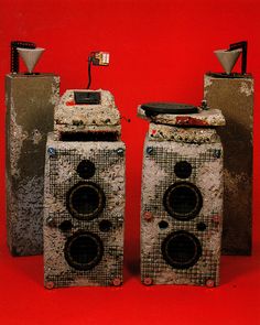 two old speakers sitting next to each other on top of a red surface with one speaker missing