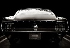 a black and white photo of an old mustang in the dark with its hood up