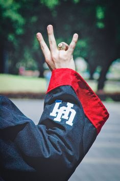 a person holding their hand up in the air and wearing a jacket with letters on it