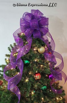 a decorated christmas tree with purple ribbon and ornaments