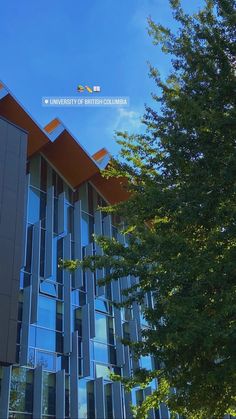 a tall building with many windows and trees in front of it on a sunny day