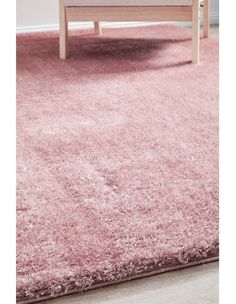 a living room with pink rugs on the floor and a couch in the background