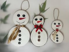 three snowmen made out of toilet paper are hanging from twine with ribbons on them