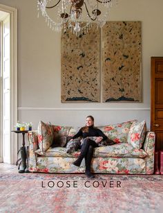 a man sitting on top of a couch next to a chandelier