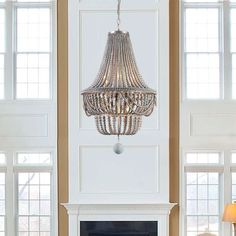 a living room filled with furniture and a fire place under a chandelier hanging from the ceiling