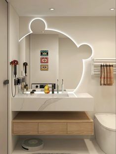 a bathroom with a sink, toilet and mirror that has mickey ears on the side