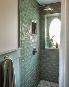 a bathroom with green tiles and a window