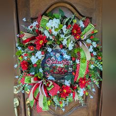 a wreath on the front door of a house with flowers and berries hanging from it