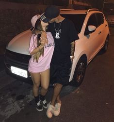 a man standing next to a woman in front of a car