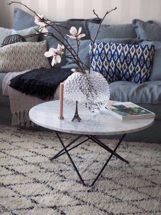 a living room with a couch, coffee table and flowers on the end table in front of it