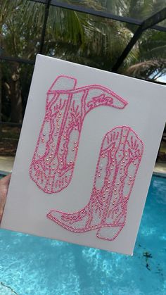 a person holding up a card with the letter u in it's hand next to a swimming pool