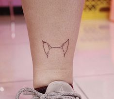 a small tattoo on the ankle of a woman's foot with a cat head