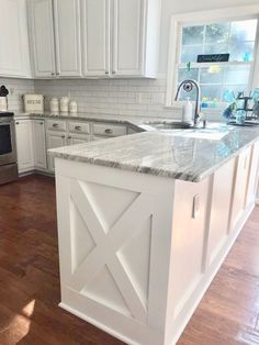 a large kitchen with white cabinets and marble counter tops, an island in the middle