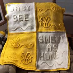 a yellow and white crocheted blanket on top of a bed